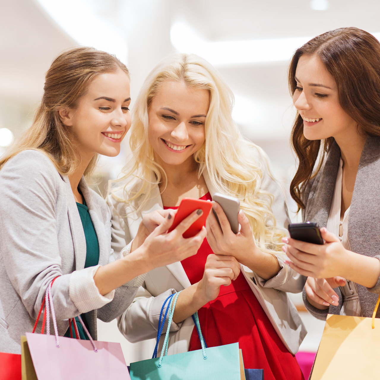 A group of friends holding many shopping bag and browsing their phones to find their desired items.