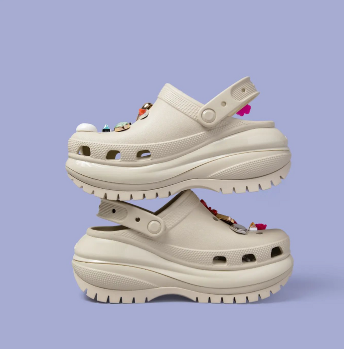 Display of white Crocs shoes featuring Jibbitz charms.