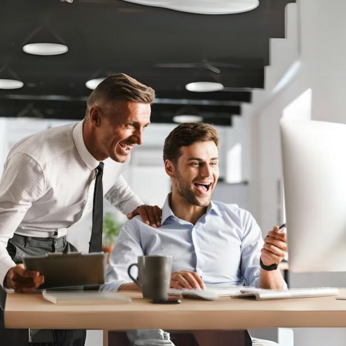 Two employees are looking at a computer and discussing work.