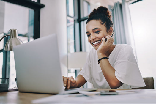 Female store owner smiling happily while looking at her laptop.