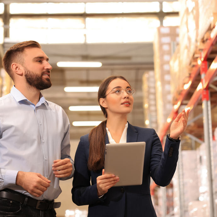 Two executives are overseeing operations in the warehouse.