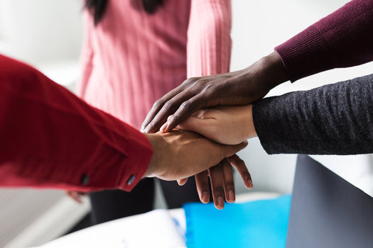 Employees stacking their hands together in a gesture of teamwork and collaboration.