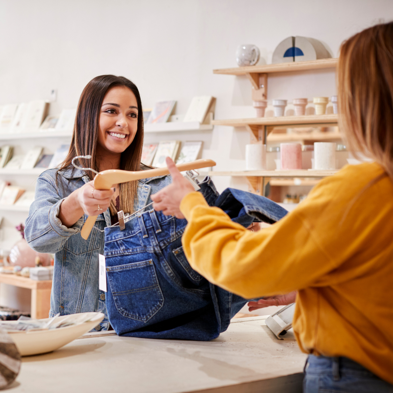 Customer handing her favorite clothing items to the store employee for checkout.
