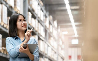 Employee using ipad to manage warehouse inventory.