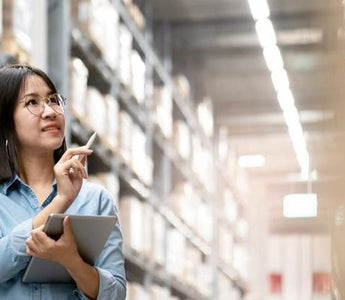 Employee using ipad to manage warehouse inventory.