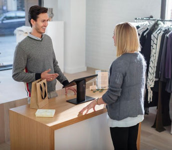Retail employee processing a customer's purchase using a POS system.