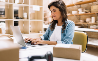 Business owner reviewing and processing customer orders in her office.
