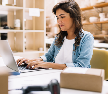 Business owner reviewing and processing customer orders in her office.