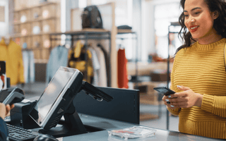 Customer holding a bank card while checking out at a retail store counter.