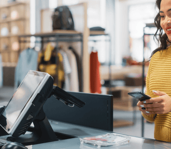 Customer holding a bank card while checking out at a retail store counter.