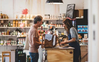 Customer handing selected items to a retail cashier at the checkout counter.