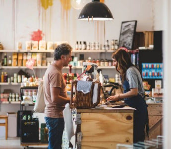 Customer handing selected items to a retail cashier at the checkout counter.