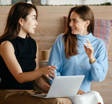 Female employee holding a laptop, explaining a solution to a client.